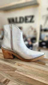 Botas tejanas de cuero charolado negro, con taco cuadrado de 7 cm y punta fina. Cuentan con cierre interno y costuras visibles en la suela.