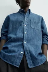 Camisa regular fit de denim de algodón azul, con cuello solapa, manga larga con puños abotonados, un bolsillo de parche en el pecho y cierre frontal de botonadura.