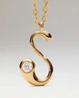 Collar de oro con dije de letra S que incluye una circonia incrustada en el extremo inferior, suspendido de una fina cadena de eslabones.
