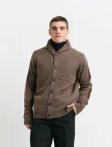 Cardigan de punto color marrón con cuello esmoquin, cierre frontal con botones y presilla superior. Presenta mangas largas con coderas en contraste y bolsillos frontales de ribete.