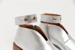 Botín de cuero color borgoña con taco bajo, corte en V en el empeine, pulsera con detalles metálicos y cierre lateral.