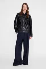 Chaqueta de cuero negro, estilo oversize con costuras a tono, botones plateados, bolsillos con solapa en el pecho y bolsillos laterales.