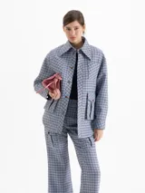 Chaqueta de twill en tono celeste con estampado de cuadros, corte camisero y largo por debajo de la cadera. Presenta cuello clásico, cierre frontal con broches forrados en cuero y bolsillos frontales tipo cargo.