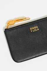 Monedero de piel vacuna con estructura blanda, cierre de cremallera con tirador de cordón y logo metálico frontal. Cuenta con bolsillo interior y placa metálica logotipada.