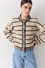 Cardigan rojo de punto amplio con rayas horizontales azul marino, mangas largas abuchonadas y cuello redondo. Cuenta con cierre frontal de botones, detalles en los bordes y un pequeño bordado de raqueta de tenis en el pecho.