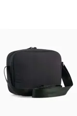 Bandolera Puma modelo 092184, color negro, de diseño rectangular con compartimento principal con cierre, bolsillo frontal con cremallera y correa ajustable para el hombro. Incluye el logo de la marca estampado en plateado.