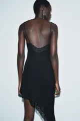 Vestido midi de estilo lencero confeccionado en viscosa, con escote en pico, tirantes finos y detalle de encaje a tono. Presenta un diseño con bajo asimétrico.