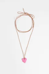 Collar largo de cordón marrón con dije colgante en forma de uva de color rosado brillante.