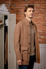 Chaquetón de lana con mezcla de seda en color tostado, con cuello alto, cierre frontal de botones y bolsillos delanteros con solapa.