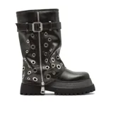 Bota de caña media en cuero sintético negro con plataforma dentada. Presenta un diseño con múltiples ojales metálicos plateados distribuidos por toda la caña, cierre lateral con cremallera y una tira con hebilla ajustable en la parte superior.