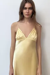Vestido midi de tejido satinado en color amarillo, con escote en pico, tirantes finos ajustables, detalles de frunces en el pecho y falda de corte fluido.