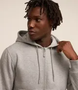 Buzo deportivo negro con capucha, cierre frontal con cremallera, bolsillos laterales y puños ajustados. Confeccionado en tejido de algodón y poliéster.