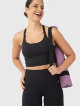 Top deportivo tipo crop top color negro con sujetador interior integrado, escote redondo y diseño de tiras finas cruzadas en la espalda.