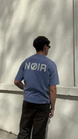 Remera celeste con estampado frontal en blanco, corte boxy y cuello redondo. Pantalón marrón de corte ancho y zapatillas deportivas blancas.