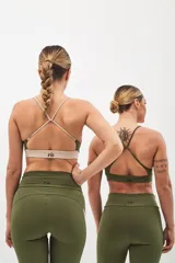 Top deportivo color beige con contorno inferior y tiras cruzadas en la espalda color borgoña. Cuenta con almohadillas removibles.