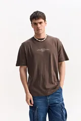 Remera oversize de manga corta color marrón con estampa pequeña en el pecho y estampa geométrica en la espalda.
