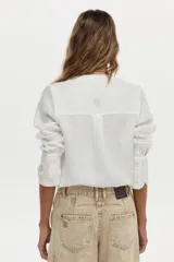 Camisa blanca de lino con cuello mao, manga larga y delicados bordados en tono tostado en el pecho y los puños.