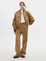 Pantalón jean de tiro alto y corte pinzado, con perneras de caída suelta y levemente anchas en el bajo. Posee pasador con hebilla en la parte trasera.
