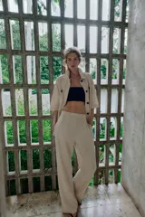 Pantalón de tiro medio confeccionado en lino color beige, de pernera recta con nervios marcados en el delantero. Posee bolsillos frontales, falsos bolsillos de vivo en la espalda y cierre frontal con cremallera, botón interior y gancho.