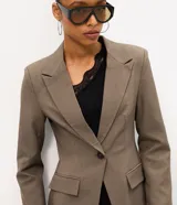 Blazer de sastrería ajustado color marrón, con cuello de solapa clásica, cierre frontal de un botón y bolsillos delanteros con solapa.