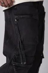 Jean baggy de corte holgado con múltiples bolsillos cargo frontales con cierre metálico. Presenta un acabado lavado, tiro medio y tiras de ajuste en la botamanga.