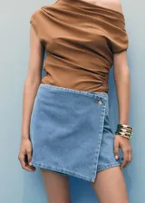 Short pollera de denim con diseño cruzado, tiro medio y cierre frontal con botón. Presenta un corte recto y estilo clásico de jean.
