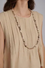 Blusa color beige con alforzas en la parte delantera y trasera, cuello redondo y mangas cortas con bordados artesanales.