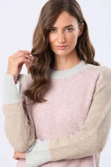 Buzo tejido de abrigo con bloques de color en rosa, beige y gris claro. Tiene cuello redondo y mangas largas.