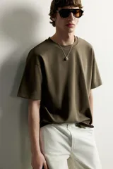 Remera de corte holgado color gris oscuro, con cuello redondo y mangas cortas. Confeccionada en tejido suave con mezcla de modal.