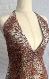 Vestido corto ajustado con escote profundo en V y cuello halter, cubierto completamente de lentejuelas con patrón moteado en tonos marrones, naranjas y blancos.