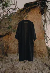 Kimono de largo midi en color negro, con diseño de calce relajado y fluido. Presenta mangas amplias y una caída natural, ideal para usar como capa liviana sobre otras prendas.