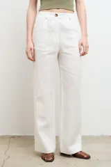 Pantalón de vestir color beige, de corte recto y tiro alto, confeccionado en lino 100% con bolsillos laterales.