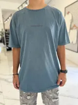 Remera de corte oversize color azul, con efecto gastado y pequeño texto bordado en el pecho.