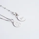 Conjunto de cadena fina y medalla circular de plata 925, con grabado lineal de figuras infantiles en el frente.