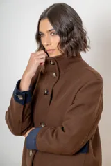 Campera de paño de lana color marrón con diseño oversize. Presenta cuello alto, cierre frontal con botones y detalles en pana azul marino en los puños y en las tapas de los bolsillos frontales.