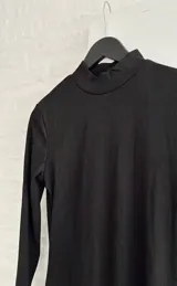 Vestido corto negro de cuello alto y manga larga, confeccionado en tejido ajustado al cuerpo.