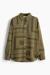 Camisa verde militar con estampado geométrico de líneas blancas, cuello clásico, botones frontales y mangas largas con puños abotonados.