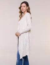 Cardigan largo de punto liviano con estampado paisley en tonos beige y blanco, de frente abierto y manga larga.