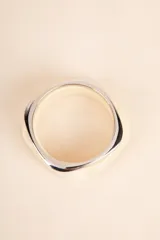 Set de dos pulseras rígidas con forma cuadrada, una color crema con efecto marmolado y otra plateada.