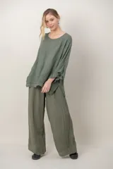 Blusa de lino color verde militar, holgada, de manga 3/4 con volados en los puños, cuello redondo y detalle de alforzas horizontales en el dobladillo.