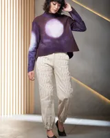 Pantalón babucha color beige de algodón, con corte a la cintura y piernas levemente amplias. Presenta textura de tablitas centrales y elásticos con broches inferiores que ajustan las piernas al tobillo.