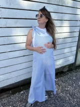 Mono largo de corte holgado con diseño de rayas verticales finas en azul y blanco. Presenta breteles anchos para atar sobre los hombros y piernas de corte ancho tipo palazzo.