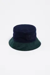 Gorro tipo bucket de pana con diseño bicolor, presentando la parte superior en azul marino y el ala en verde oscuro. Incluye el logo de la marca bordado en el mismo tono en la parte frontal.