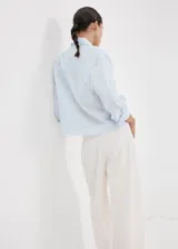 Camisa de corte recto y diseño a rayas con cuello camisero, manga larga con puños abotonados y cierre delantero con botones.