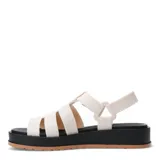 Sandalias de plataforma tipo jaula con tiras anchas de material sintético en color blanco hueso, cierre de velcro en el tobillo y suela de goma negra con base color caramelo.