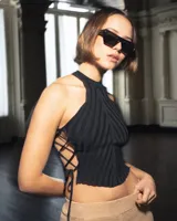 Top de punto sin mangas con cuello alto y diseño acanalado. Presenta un ajuste lateral mediante cordones entrecruzados que dejan los costados descubiertos.