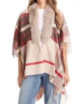 Ruana tejida con diseño a cuadros en tonos beige, rojo y marrón. Presenta un cuello con aplique de piel sintética y terminación en flecos en los bordes.