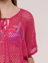 Poncho de tejido calado color beige, con mangas cortas, aberturas laterales y lazos ajustables en el cuello. Modelo Do Everything In Love.