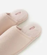 Pantufla abierta de diseño texturizado con interior de peluche y suela de goma termoplástica.