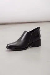 Botines de cuero negro con diseño moderno, silueta estilizada y punta fina. Cuentan con un corte en V en el lateral y tacón cuadrado de altura media.